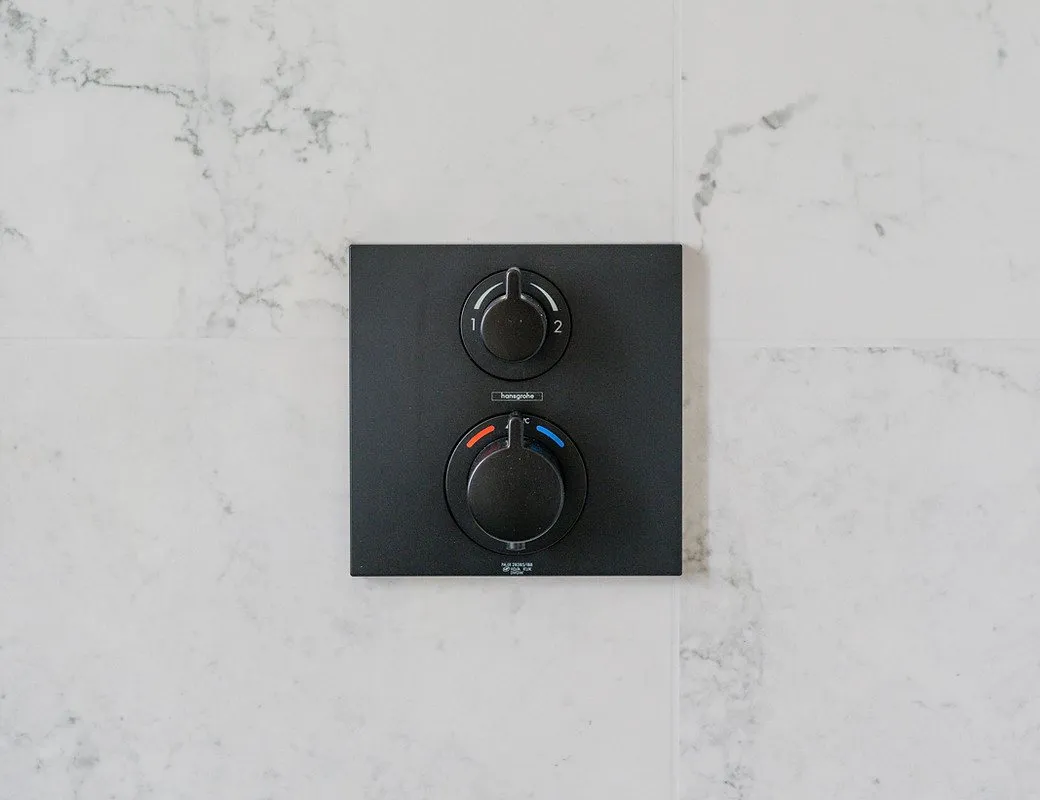 Matt black shower controls on marble